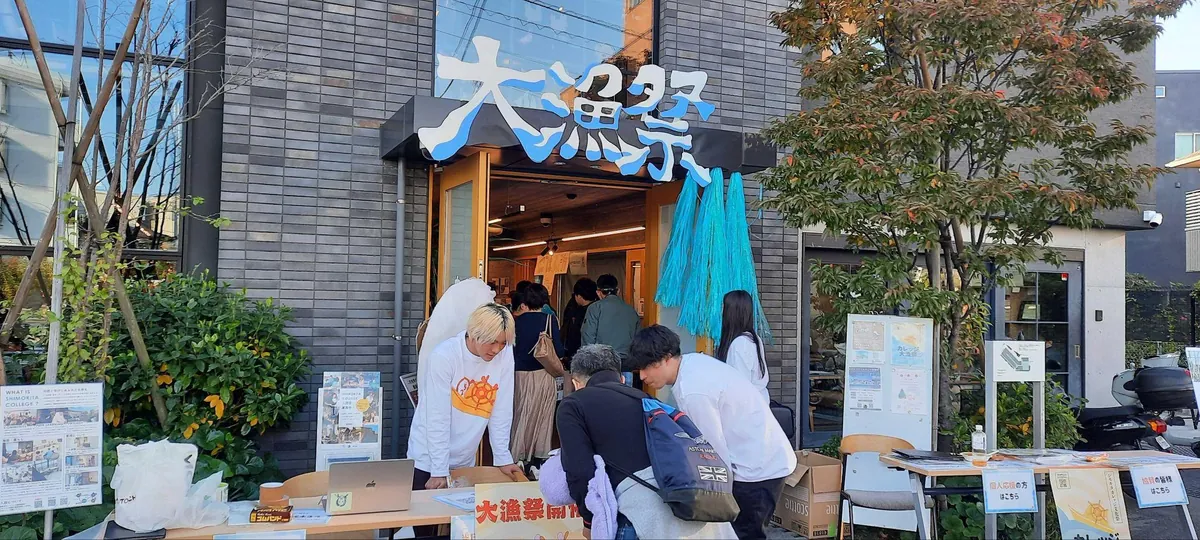 大きな文化祭の看板を掲げた会場入口で、カレッジ生が来場者を迎えている。