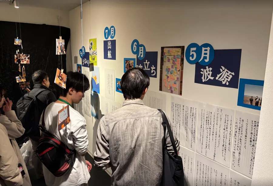壁に並んだ活動紹介のパネルや写真を、来場者がじっくりと見ている。